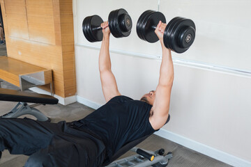 Asian male performing dumbbell chest press workout