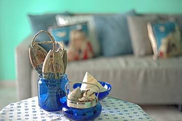 Marine style in the apartment interior - a sofa with pillows and a table with shells and fish figures.