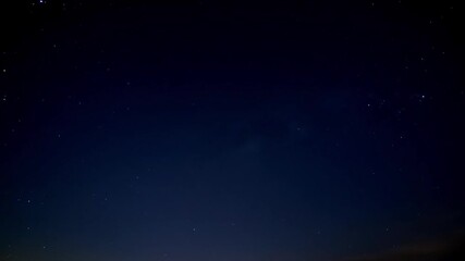 A serene timelapse of the night sky with twinkling stars and drifting clouds moving across the deep blue expanse - Powered by Adobe