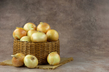 Lots of onions in a wicker basket. Vegetables in the form of onions. There is space for text.