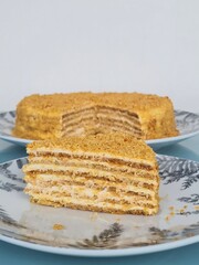 Homemade honey cake layered dessert with cream filling sliced on decorative plate showing multiple cake layers and sweet cream texture perfect for celebrations