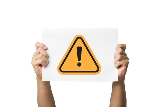 Hand holding white paper with yellow triangle caution warning sign for notification error and maintenance concept.
