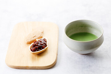 Cup of fresh matcha tea, green tea and Taiyaki, Japanese fish-shaped cake, filled with Anko or red bean on wooden plate.