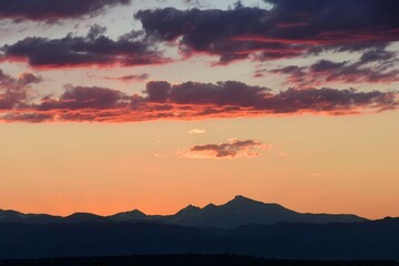 colorful, dramatic summer sunset  over long's peak and the front range of the colorado rocky mountains, as seen from broomfield, colorado