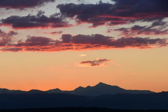 colorful, dramatic summer sunset  over long's peak and the front range of the colorado rocky mountains, as seen from broomfield, colorado