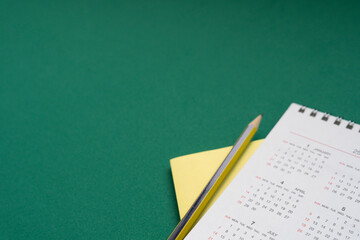 close up of calendar and pencil on the green table background, planning for business meeting or travel planning concept