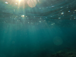 Ocean blue underwater with sunrays, Underwater Sea Deep Water Abstract Sunshine, sea wave , clean waters in summer time, Natural underwater seascape, sand on ocean floor and water surface with sunligh