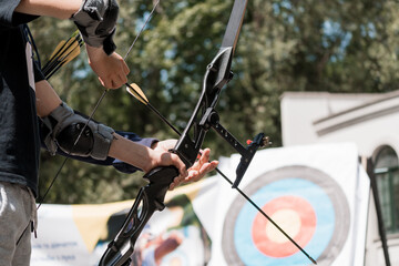 Archery Practice in Sunlight: Close-Up of Archer Drawing Bow with Arrows Aimed at Target Outdoors, Blue Shirt, Focused Action