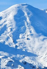 A majestic mountain peak covered in snow under a clear blue sky on a sunny day view