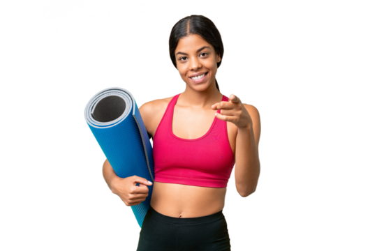 Young sport African American woman going to yoga classes while holding a mat over isolated background surprised and pointing front