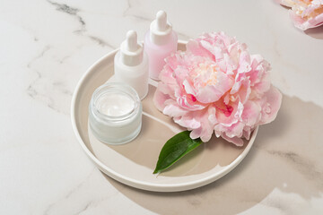 Skincare essentials paired with fresh peony blooms on a tray. botanical beauty meets luxury...