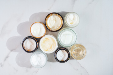 Top-down view of assorted open cream jars neatly arranged on a table, showcasing a luxurious...