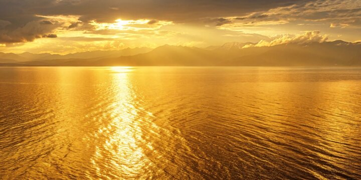 Golden sunset over calm sea and mountain range - Powered by Adobe