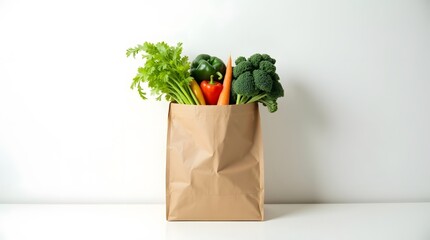A healthy paper shopping bag overflowing with fresh organic vegetables and fruit isolated on white