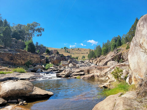 Small river flowing through a rocky valley in the Australian bush. Taken near the Adelong Falls Gold Mill Ruins under a beautiful blue sky