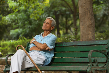 Indian old man spending leisure time at park 
after retirement