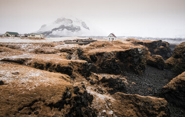 Lonely house at the small fishing village of Arnarstapi and mountain cliff covered in snow Iceland