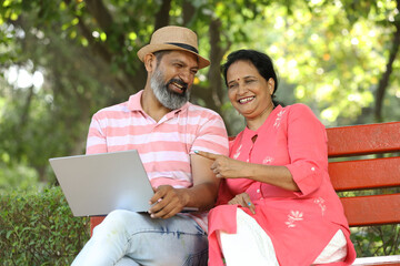Indian mature couple working on laptop in garden. Happy Elderly couple smiling carefree, mature male and female  with positive emotion. all good 