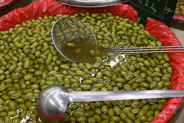 Bac d'olives vertes avec une passoire et une louche