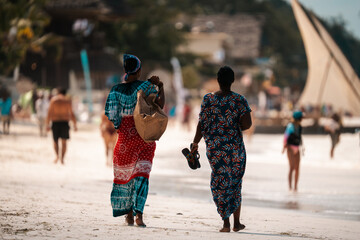 Women wearing African dress walking on a beach in Zanzibar