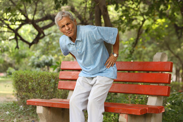 Fototapeta premium Indian Senior man suffering from back pain in the park.