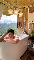 Handsome Man Relaxing in Bubble Bath with Stunning Mountain Sunset View
