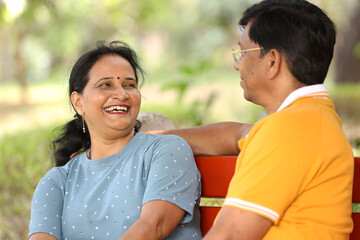 Fototapeta premium Indian happy senior couple enjoying, talking, laughing, relaxing and fun at park spend time together, relationship and people concept. Concept : Elder and Mature Couple Lifestyle