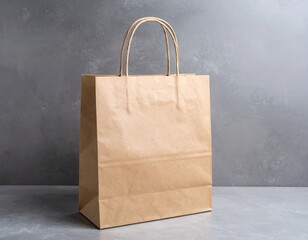 Simple brown paper shopping bag with handles on a gray textured surface