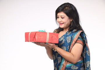 Indian beautiful happy woman holding gift boxes and standing on white background. wearing...
