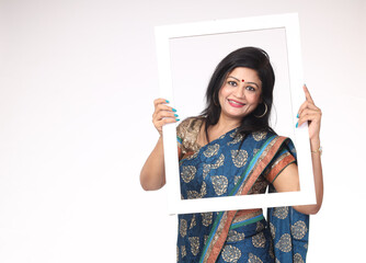 Smiling Attractive Beautiful Indian happy Woman holding photo frame shaped white carboard while...