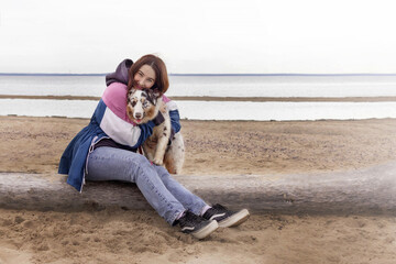 A woman hugs her Aussie Australian Shepherd dog in blue marble color and different eye color while...