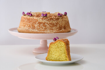 Delicious Pistachio Semolina Cake topped with toasted sesame seeds and delicate dried rosebuds on cake stand side view of gourmet dessert menus tea time