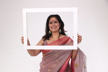 Smiling Attractive Beautiful Indian happy Woman holding photo frame shaped white carboard while...