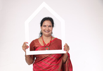 Indian happy Woman holding  home frame white  shaped carboard while standing isolated in white...