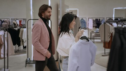 With clothes in hand, a couple makes their way to the register in a modern boutique, ready to finalize their purchase.