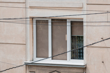 Exterior View of Beige Apartment Building Window with White Frames, Curtain and Power Lines. Urban Residential Scene, Warm Tone.