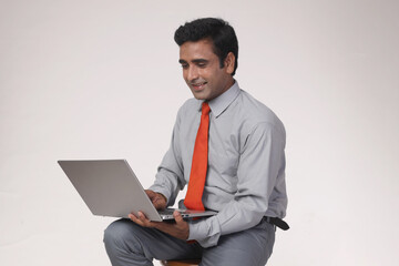 Portrait of indian young handsome smiling business man holding laptop in hands, typing and browsing web pages, isolated on white background with copy space