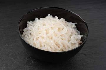 Shirataki or konnyaku pasta in black bowl. Konjak jelly noodles, Japanese zero calorie sirataki