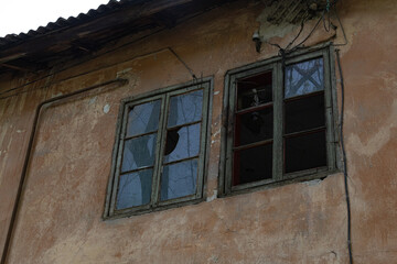 Obraz premium Broken old windows on a weathered wall of an abandoned building with visible cracks