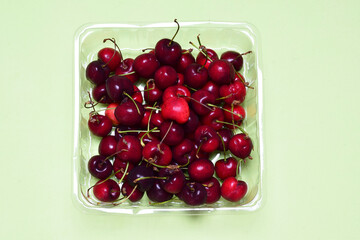 Packaging with red cherries, green background with copy space.