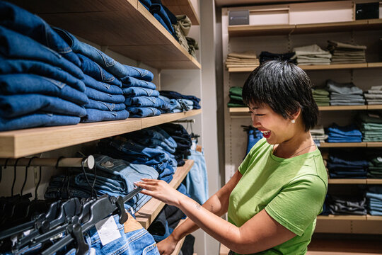 Young woman choosing jeans in clothing store