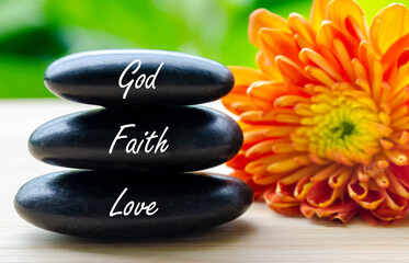 Zen stones with god, love, faith inscribed beside orange bloom