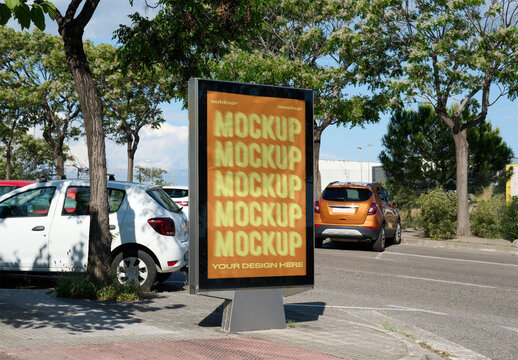 Mockup of an urban advertising panel located beside a street with parked cars, surrounded by trees in a sunny setting.