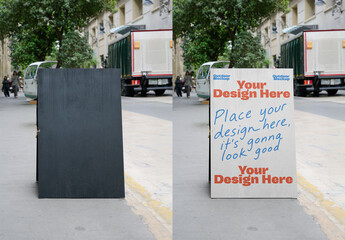 A black A-frame mockup stands on an urban sidewalk, with pedestrians and vehicles passing by, ideal for outdoor advertising displays.