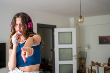 Woman Singing and Pointing with Headphones at Home – Fun Indoor Moment