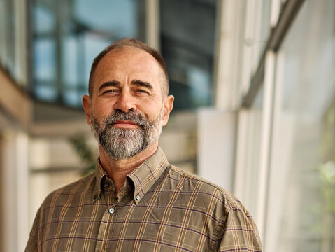Portrait of a smart inteligent senior businessman holding a laptop computer in office - Powered by Adobe