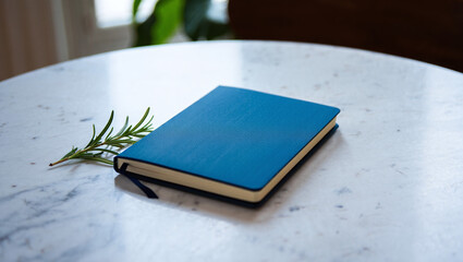 Fototapeta premium Blue Leather Notebook on Marble Table with Rosemary Sprig