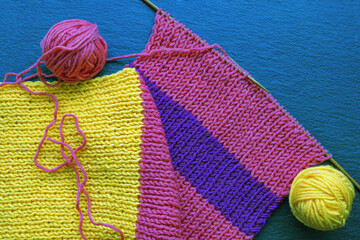 Knitting and hobbies concept.  Knitting colorful scarf. Balls of wool. Flat lay, copy space