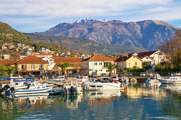 Beautiful winter Mediterranean landscape. Montenegro, Tivat city,  view of Marina Kalimanj on sunny day. Houses with red roofs, fishing boats in harbor