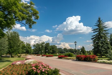 Naklejka premium Scenic park pathway with lush greenery blooming flowers and blue sky